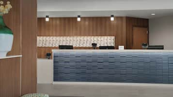 Un mostrador de recepción con un muro estampado, diseño de paneles de madera y una pared de acento azul.