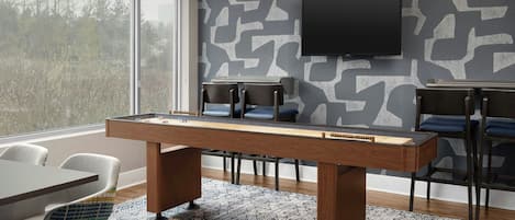 Une pièce moderne équipée d’une table de billard, de sièges confortables, d’un téléviseur à écran plat et d’un mur décoré de motifs.