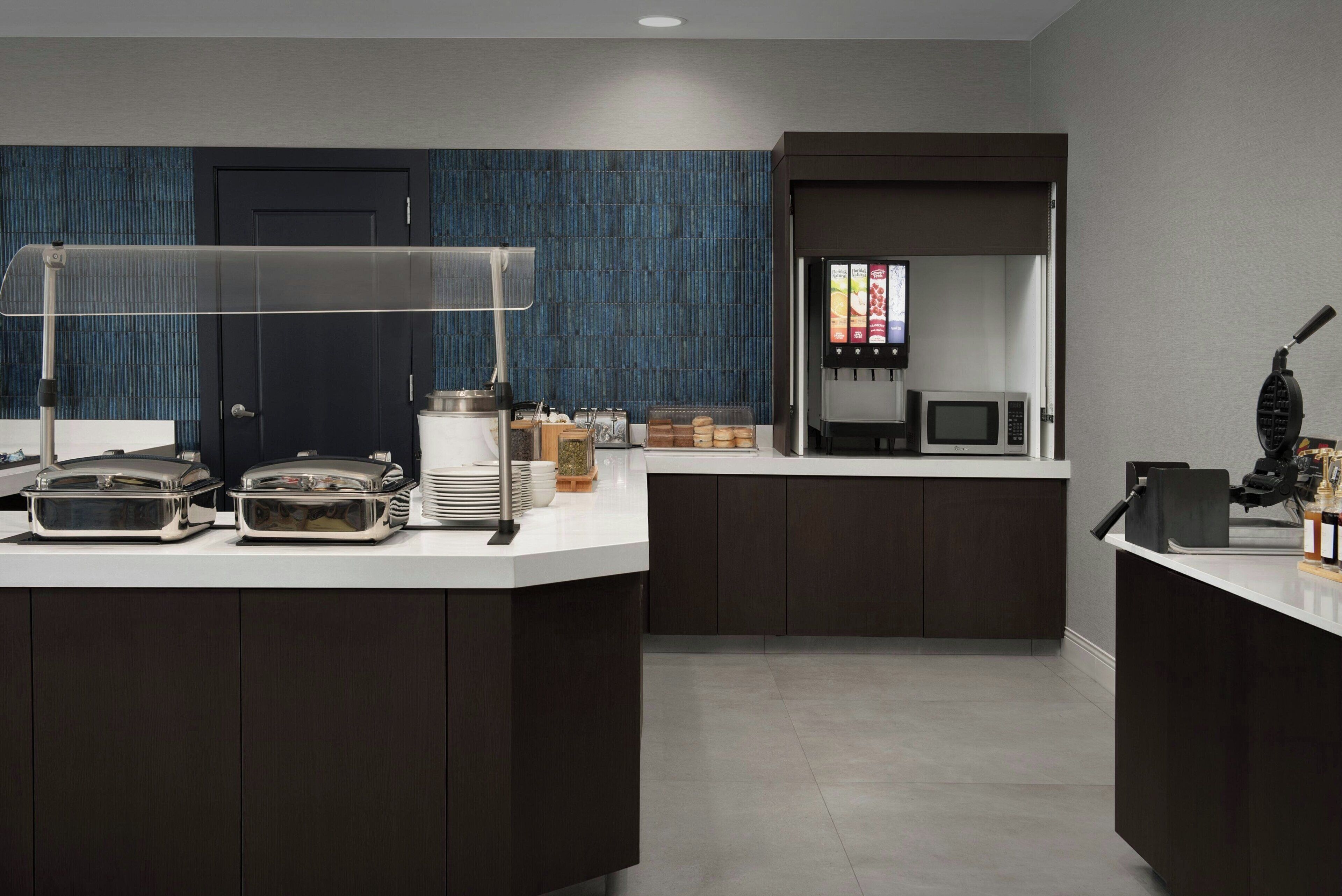 A modern kitchen with dark cabinetry, a coffee station, and a microwave.