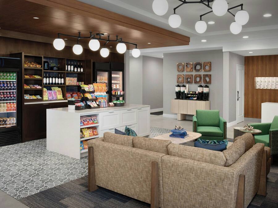 A modern lobby with a seating area, a beverage refrigerator, and a coffee station.