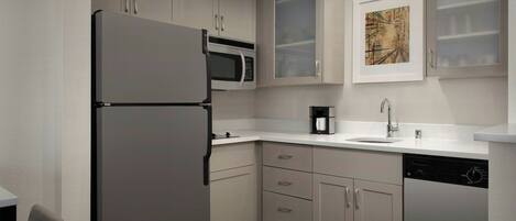 A modern kitchen with a built-in refrigerator, microwave, coffee maker, and dishwasher.
