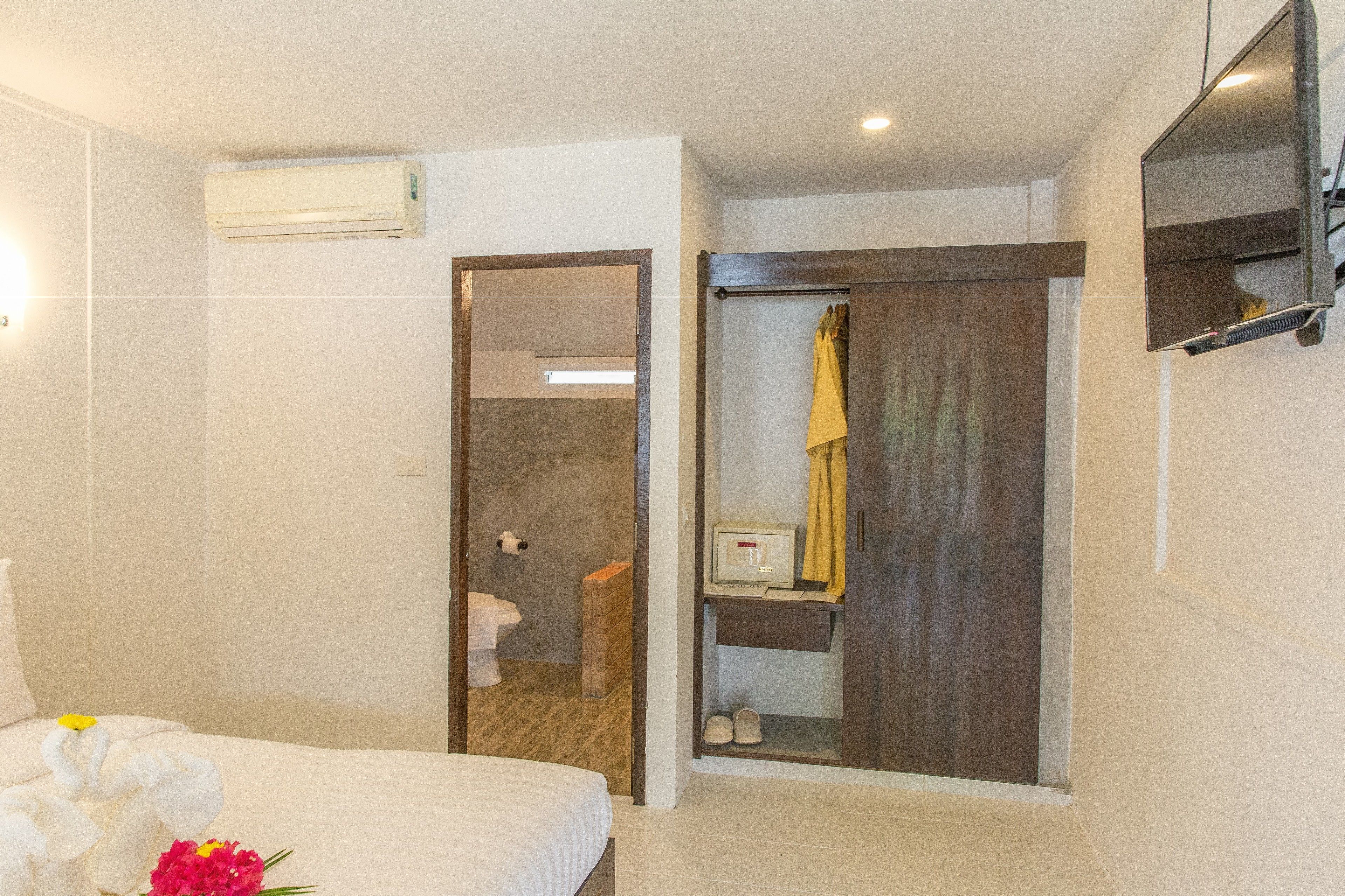 Una habitación de hotel con cama, baño con ducha y espejo en la pared.