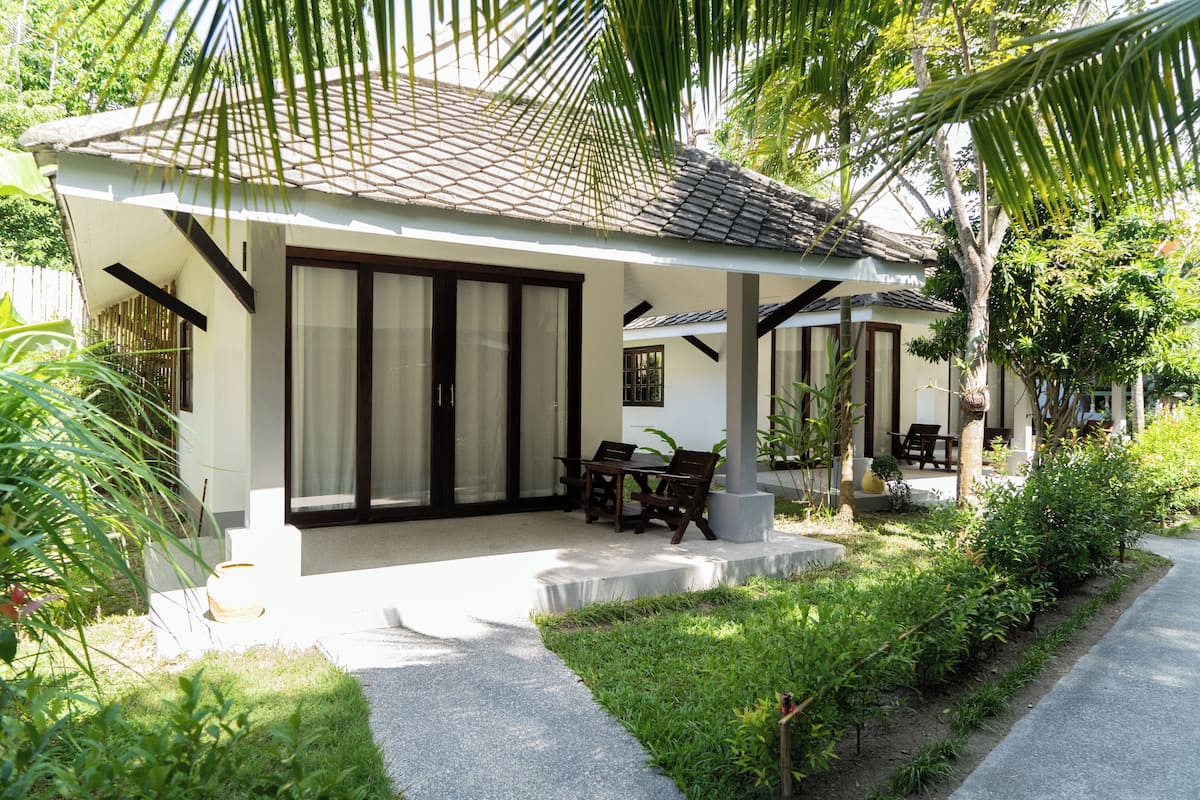 A modern house with a covered patio, a dining area, and a pathway.