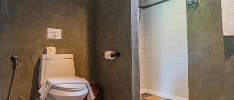 A bathroom with a toilet, a shower, and a checkered floor.