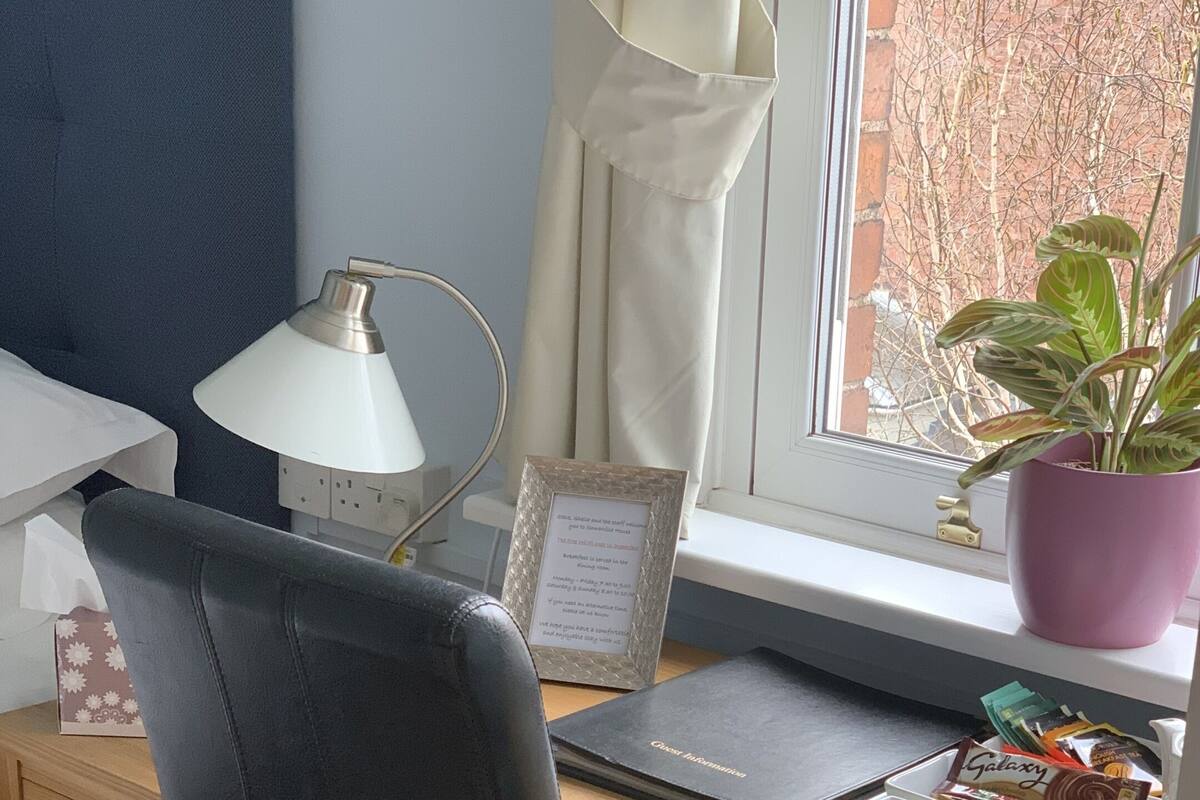 A neatly organized workspace with a laptop, a framed note, a potted plant, and a tray with snacks.