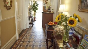 A hallway with patterned flooring, a reception desk with a vase of sunflowers, and a mirror on the wall. - Somerville House (Hereford)