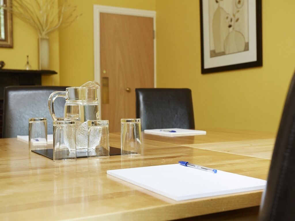 A conference room with a wooden table, clear glass pitchers, and a whiteboard.
