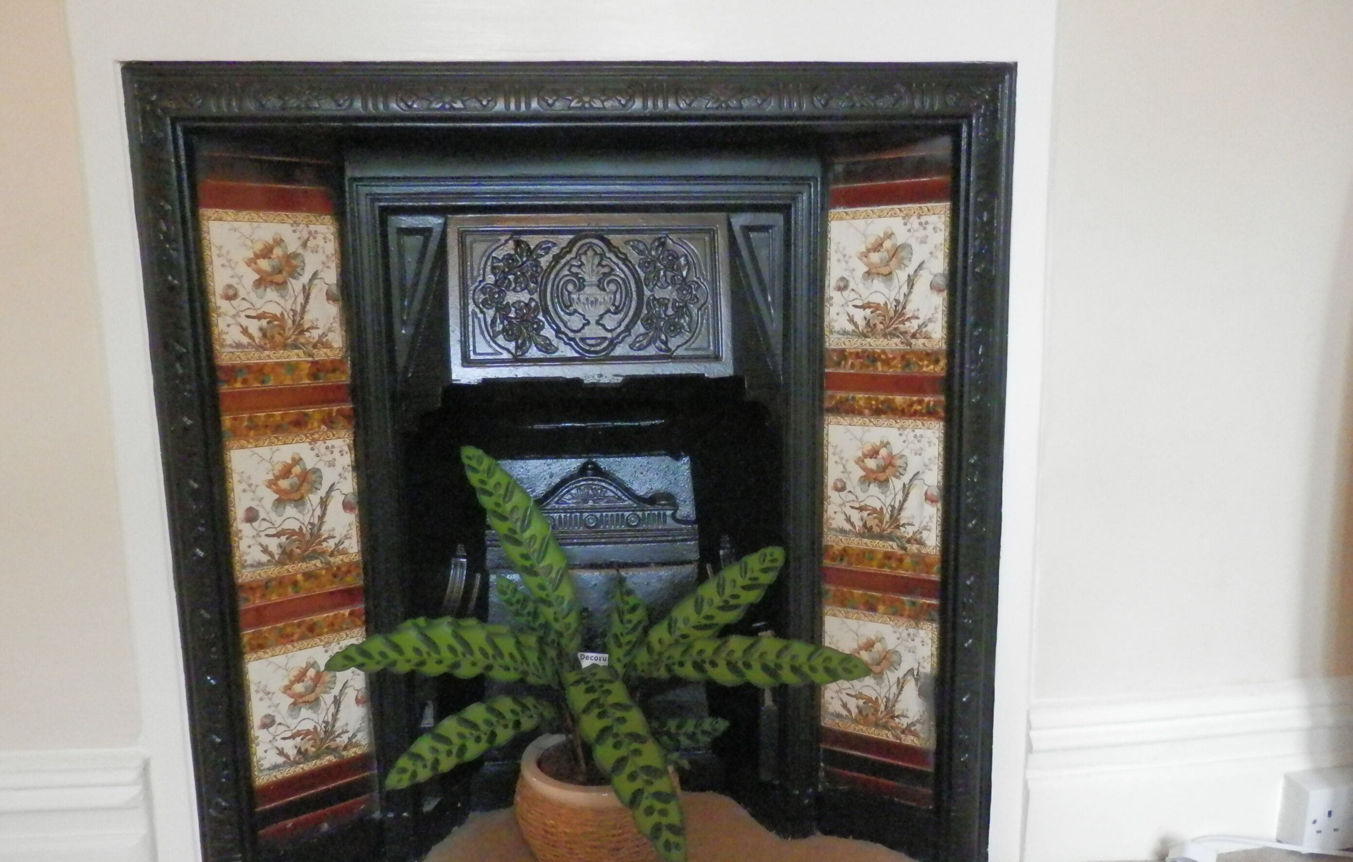 A fireplace with a decorative mantel and a potted plant in front.