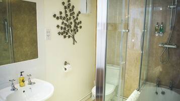 A bathroom with a glass-enclosed shower, a white sink with a soap dispenser, and a toilet.