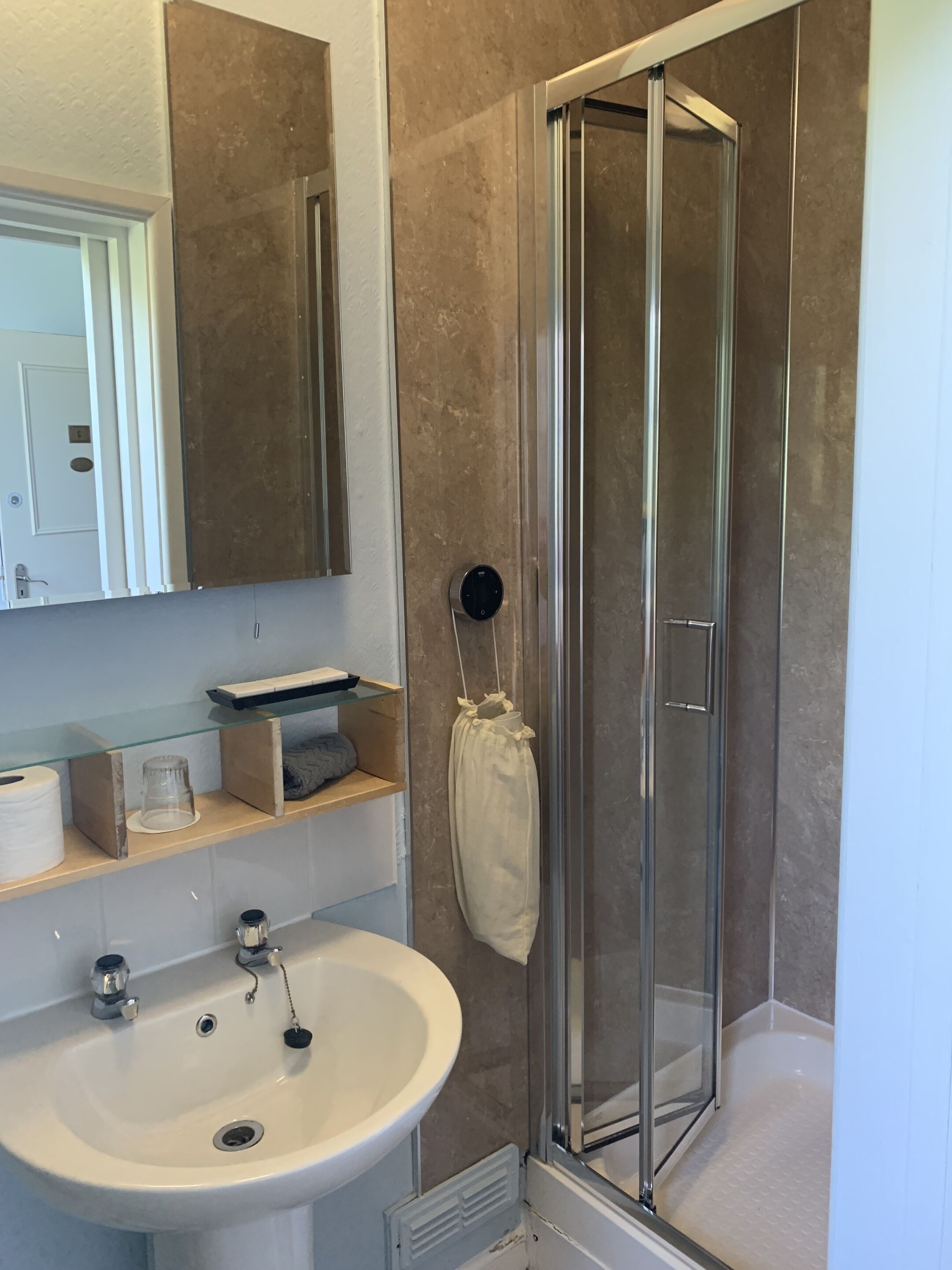 A bathroom with a glass-enclosed shower, a white sink, and a mirror above the sink.