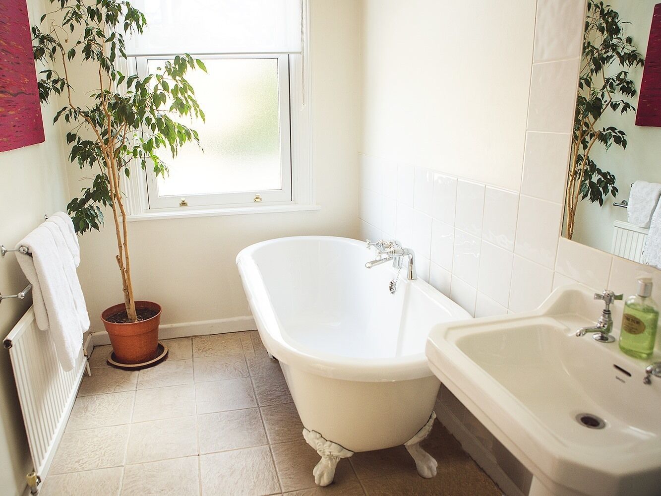 A bathroom with a freestanding bathtub, a sink, and a potted plant.