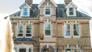 A two-story brick building with a symmetrical facade, multiple windows, and a central entrance with a door and a sign above it. - Somerville House (Hereford)