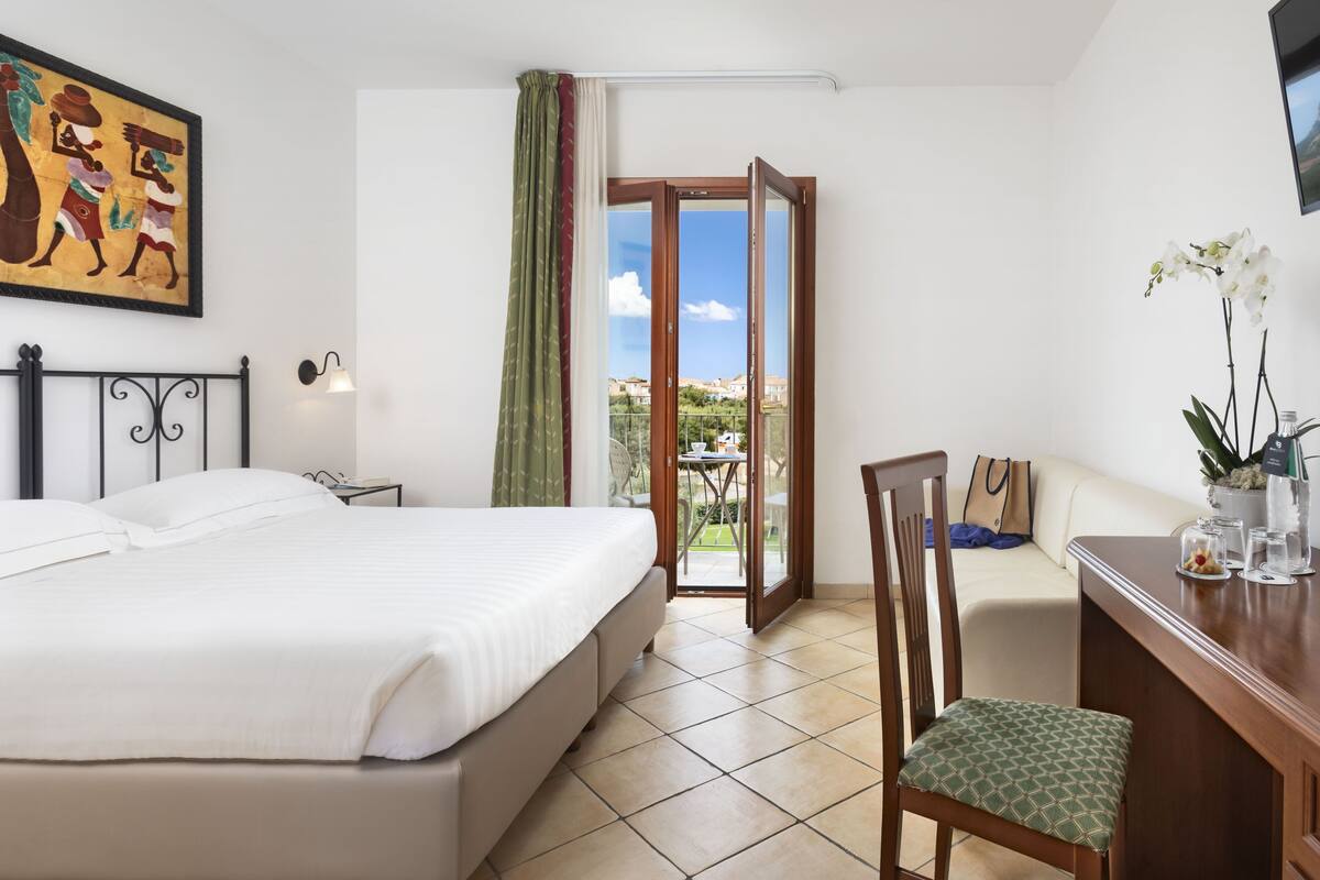 Ein Hotelzimmer mit Bett, Schreibtisch, Stuhl und Blick ins Freie.