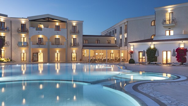 A hotel with a swimming pool, multiple balconies, and outdoor seating areas.