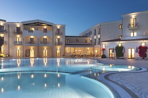 Un hotel con piscina, varios balcones y zonas de estar al aire libre.