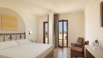 Ein Hotelzimmer mit Bett, Stuhl, Tisch und einem Balkon mit Blick.