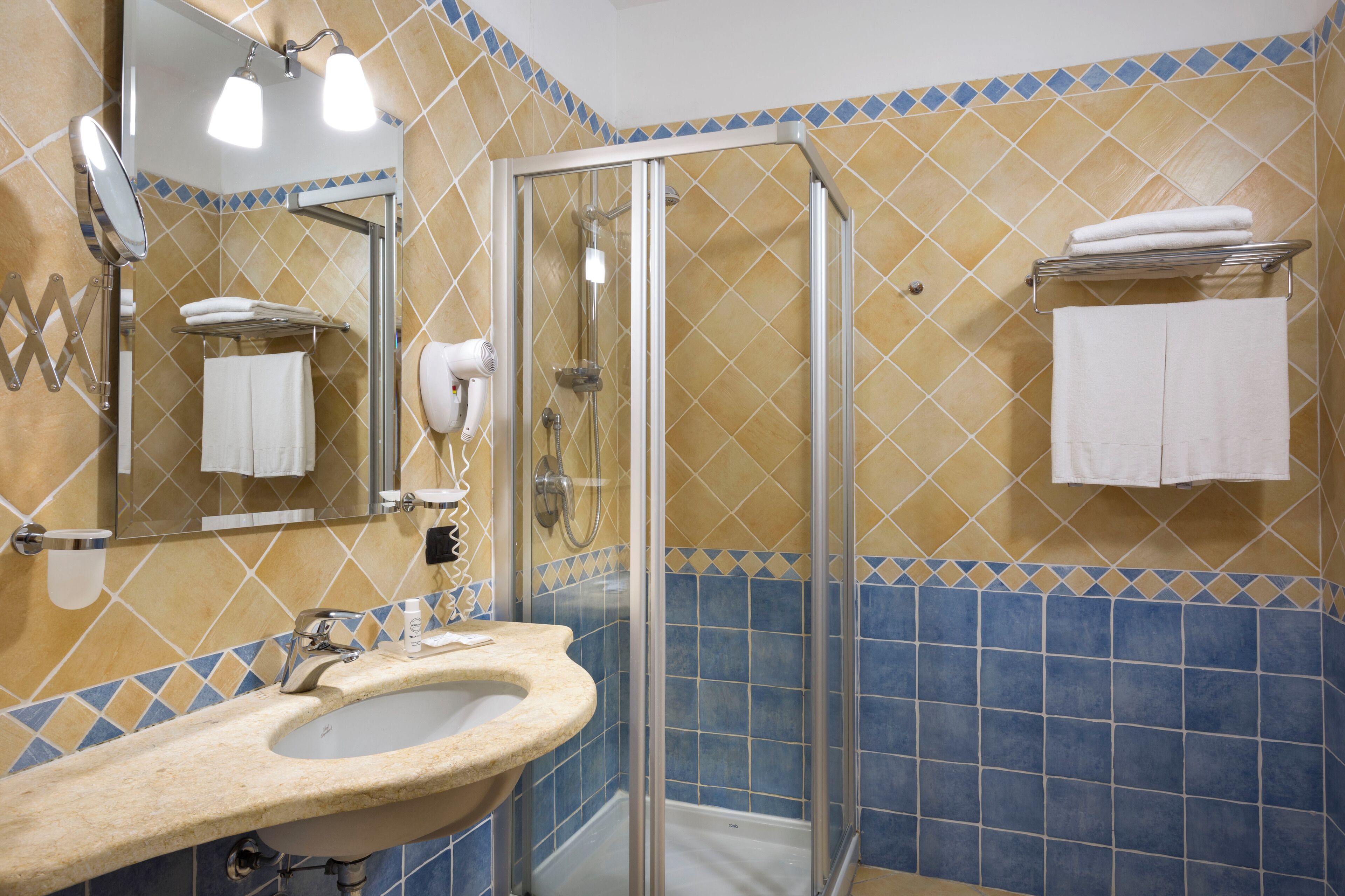 Een badkamer met een wastafel, spiegel, douche en handdoekhouder.