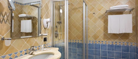 Un baño con lavamanos, espejo, ducha y toallero.