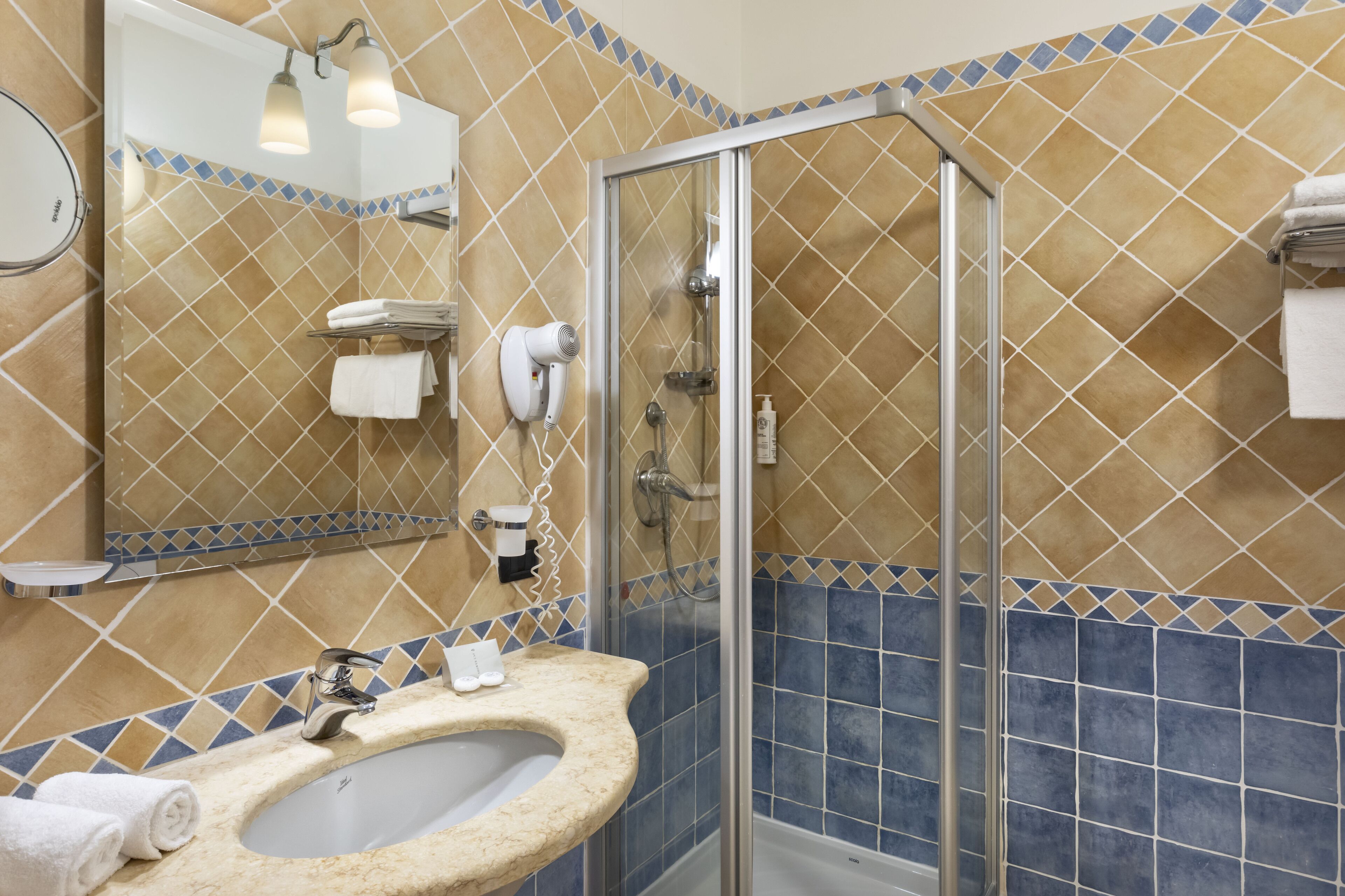 A bathroom with a sink, mirror, towel rack, and shower.