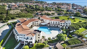 A large, multi-story hotel with a central courtyard and a swimming pool.