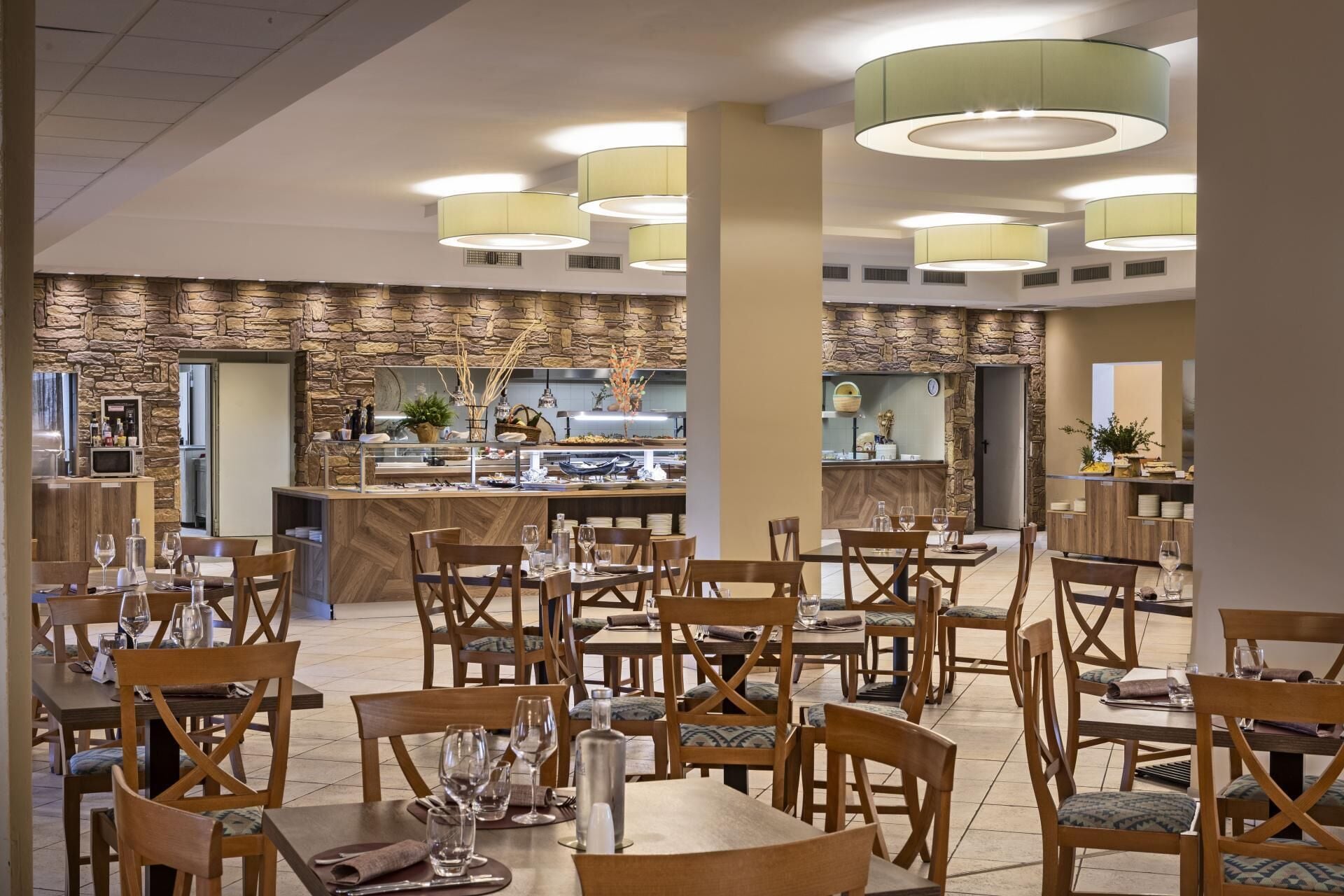 En restaurant med træborde og -stole, en stenvæg og et buffetområde.