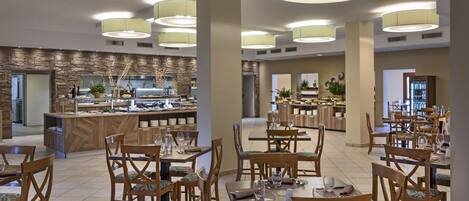A modern dining area with wooden tables and chairs, a central buffet, and pendant lighting.