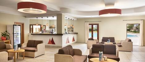 A spacious lobby with wicker furniture, a reception desk, and a pool view.