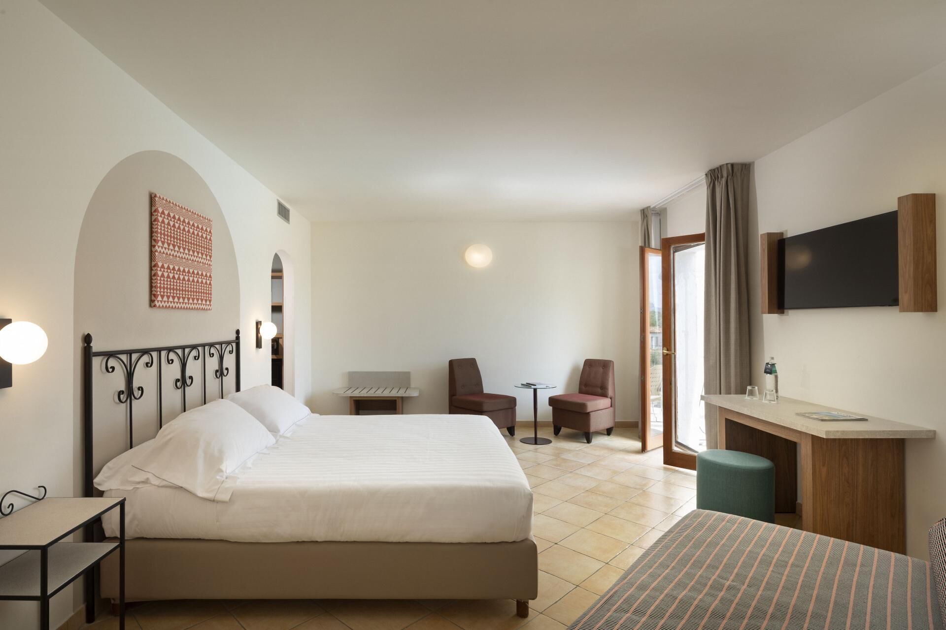 Une chambre d’hôtel avec un lit, un bureau, deux chaises, une télévision et une petite table.