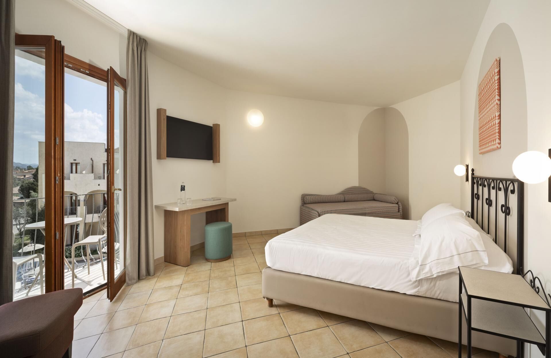 Une chambre d’hôtel avec un lit, un bureau, une chaise, une télévision et un balcon avec vue.