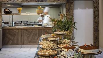 Buffet com diversos doces e um chef ao fundo.