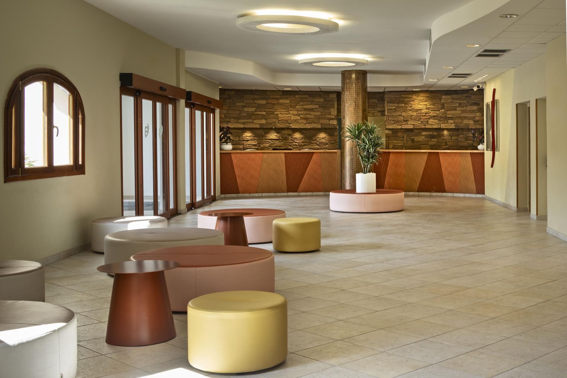 A lobby with a reception desk, a stone wall, and several seating areas.
