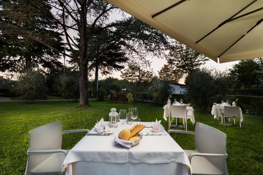 An outdoor dining area with tables set for a meal, surrounded by greenery and trees.
