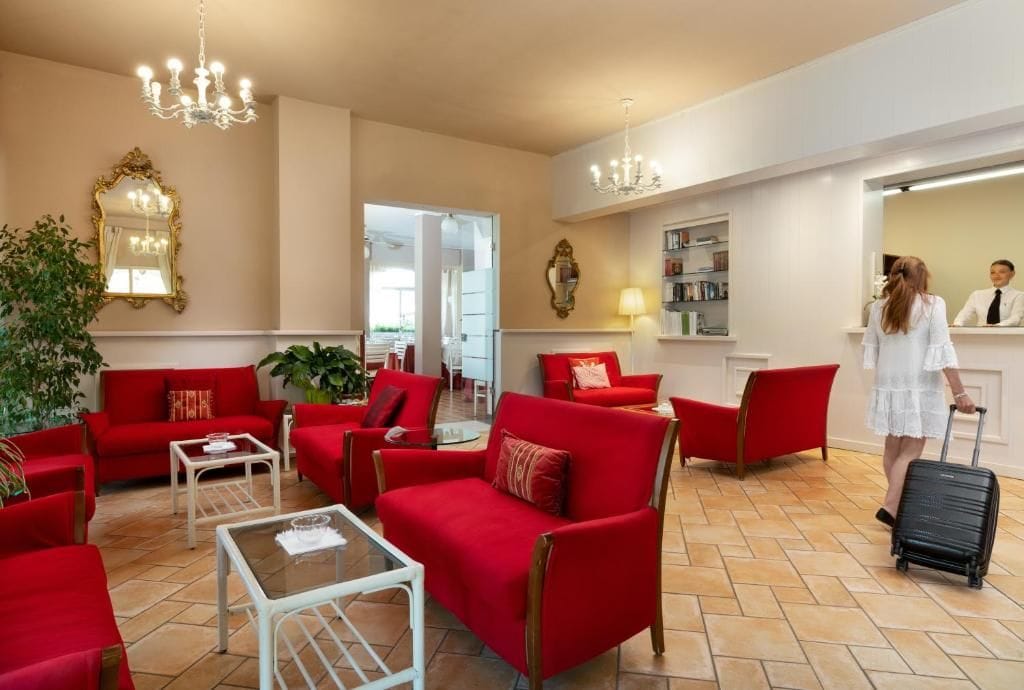 Eine Hotelhalle mit roten Sofas, einem Couchtisch, einem Spiegel und einer Rezeption.