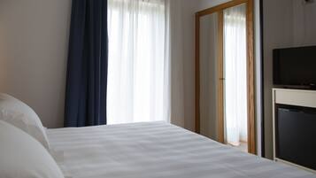 Una camera d'albergo con un letto, una televisione e un ingresso che dà su un'altra stanza.