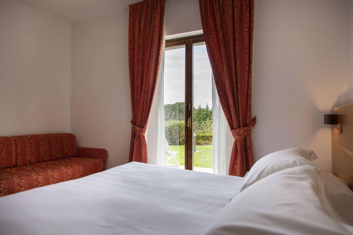 Ein Hotelzimmer mit Bett, Sofa und einem Vorhangfenster.
