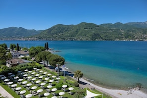 A lakeside hotel with outdoor seating, a dock, and mountains in the background.