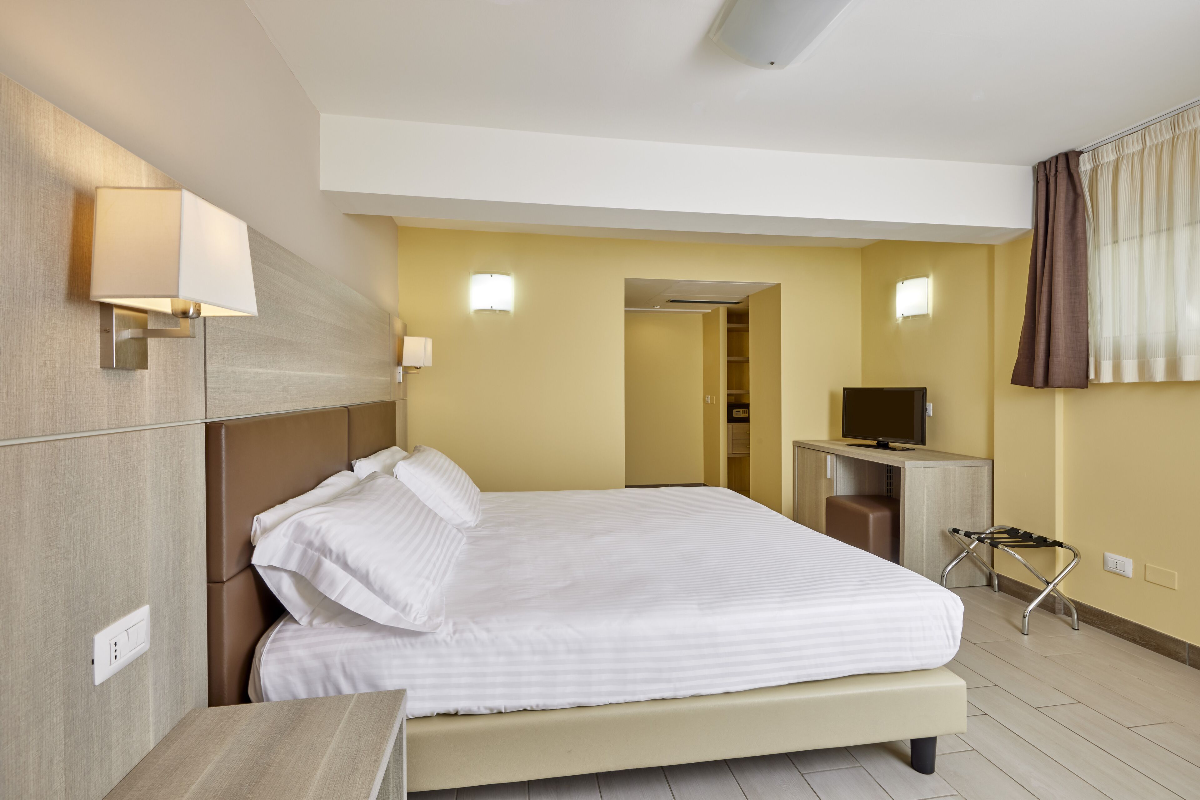 Une chambre d’hôtel avec un grand lit, des tables de chevet, un bureau et un téléviseur.