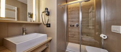 A modern bathroom with a large white sink, a glass-enclosed shower, and a toilet.