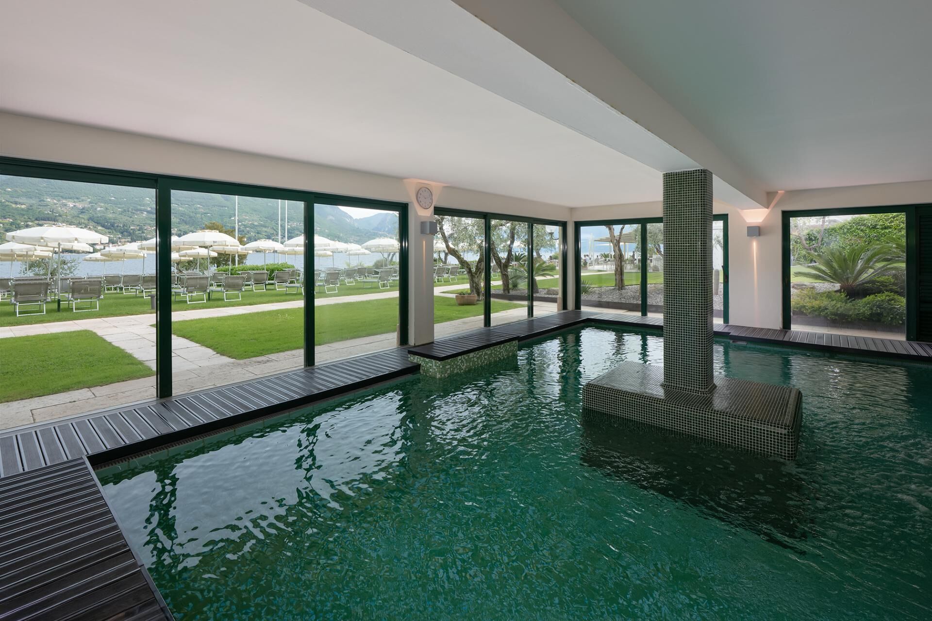 Una piscina interior con vistas a una zona ajardinada y una masa de agua.