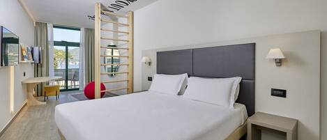 A modern hotel room with a large bed, a desk, and a view of the outdoors.