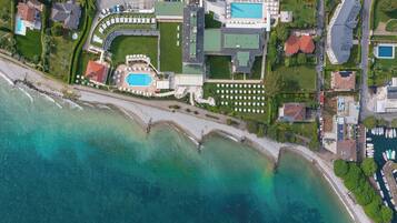 An aerial view of a coastal property with a swimming pool, tennis courts, and a marina.