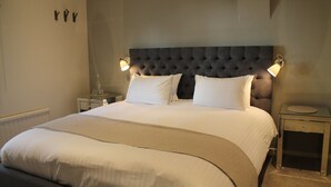 A neatly made bed with a tufted headboard, two bedside tables, and wall-mounted lamps.