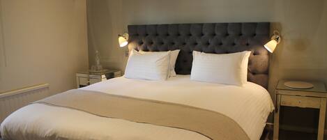A neatly made bed with a tufted headboard, two bedside tables, and wall-mounted lamps.