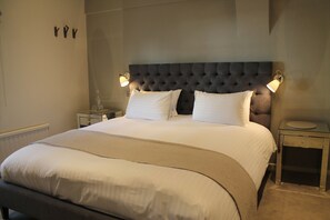 A neatly made bed with a tufted headboard, two bedside tables, and wall-mounted lamps.