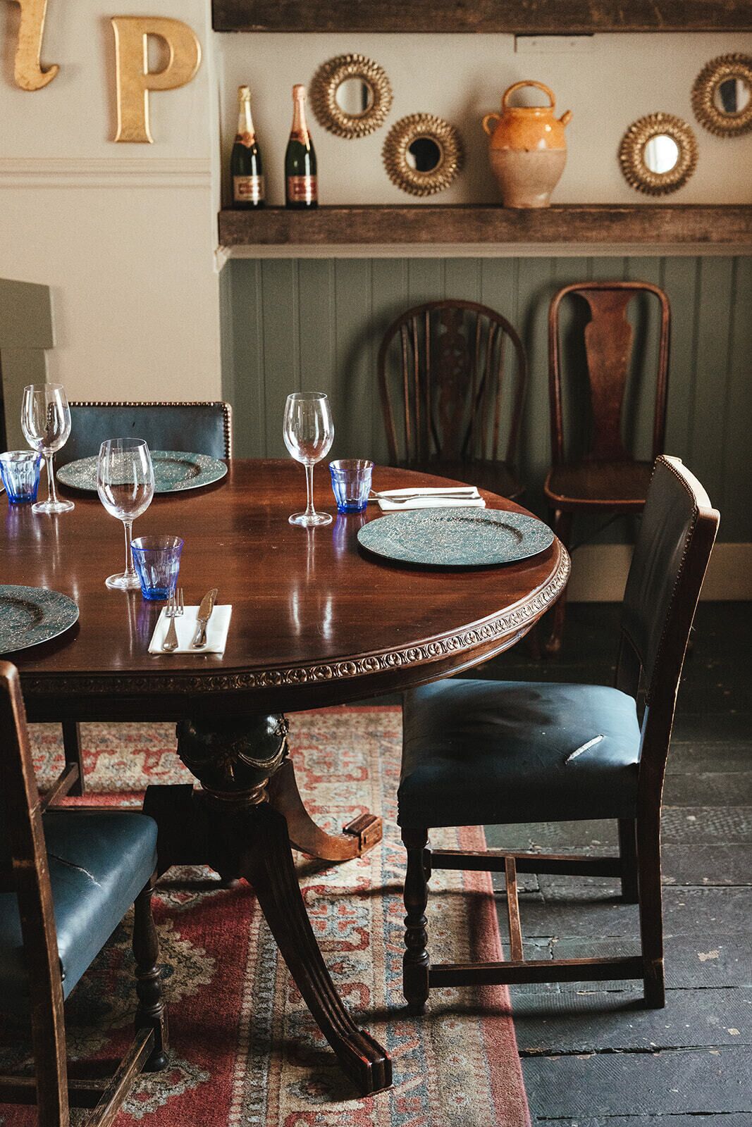 Een eettafel gedekt met borden, glazen en bestek, omringd door gestoffeerde stoelen.