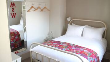 Un dormitorio con cama, mesita de noche, espejo y armario.