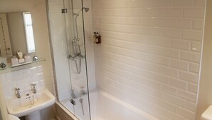 A modern bathroom with a glass-enclosed shower, a white sink, and a tiled wall.