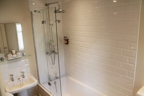 A modern bathroom with a glass-enclosed shower, a white sink, and a tiled wall.