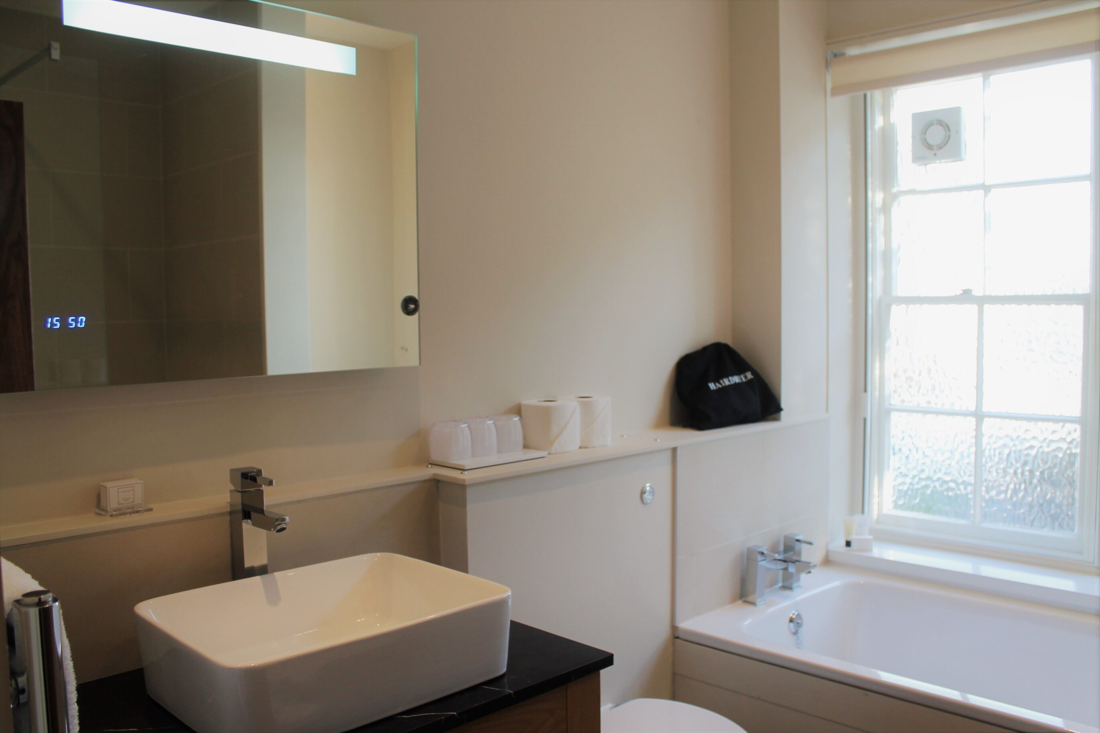 A bathroom with a white sink, a mirror, a toilet, and a bathtub.