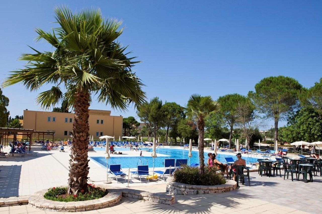 Una piscina al aire libre, sombrillas, tumbonas